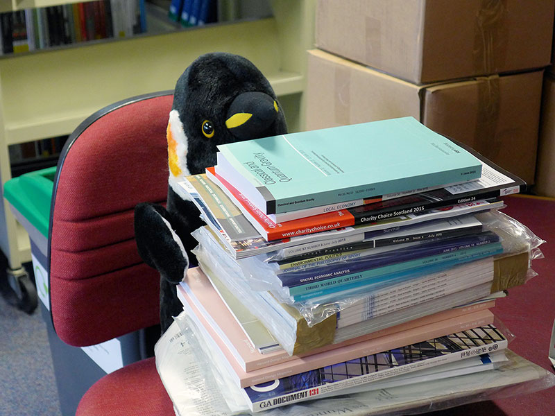 Pablo Penguin handling a stack of journals