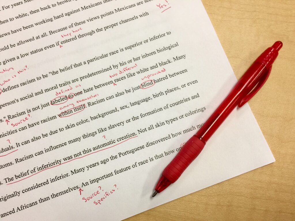 Essay marked with red pen.  From pxhere - https://pxhere.com/en/photo/1032524#google_vignette