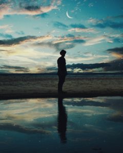 Silhouetted man reflected in water