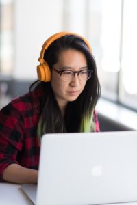 Asian woman studying with headphones and MacBook