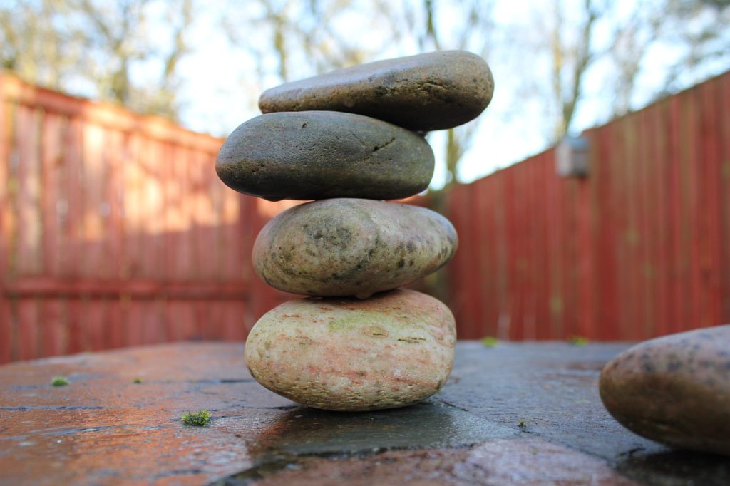 A stack of four smooth pebbles in a garden.