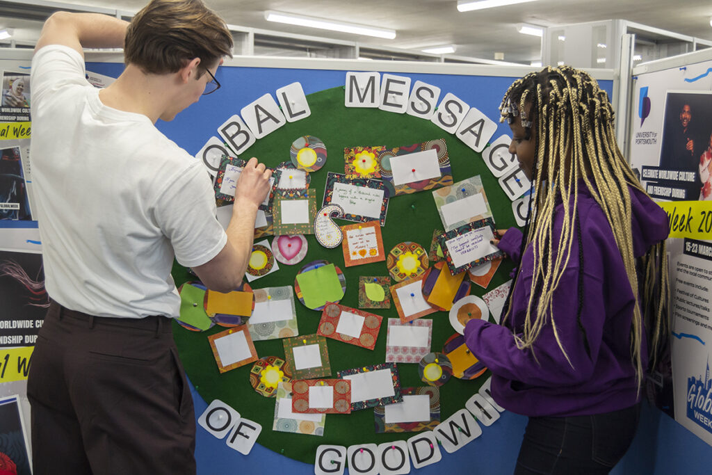 Two PGM Ambassadors pinning messages of goodwill to the display board